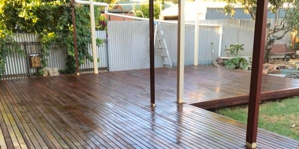 A glistening timber deck underneath a covered pergola