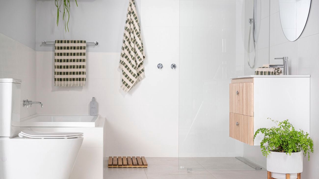 Bathroom with everything in white colour, stainless steel fittings, wooden pull drawers under sink. 