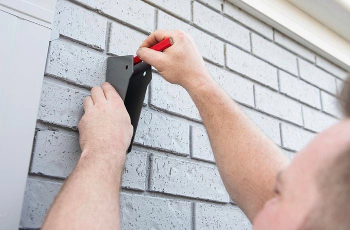 Person marking clothesline bracket position on wall