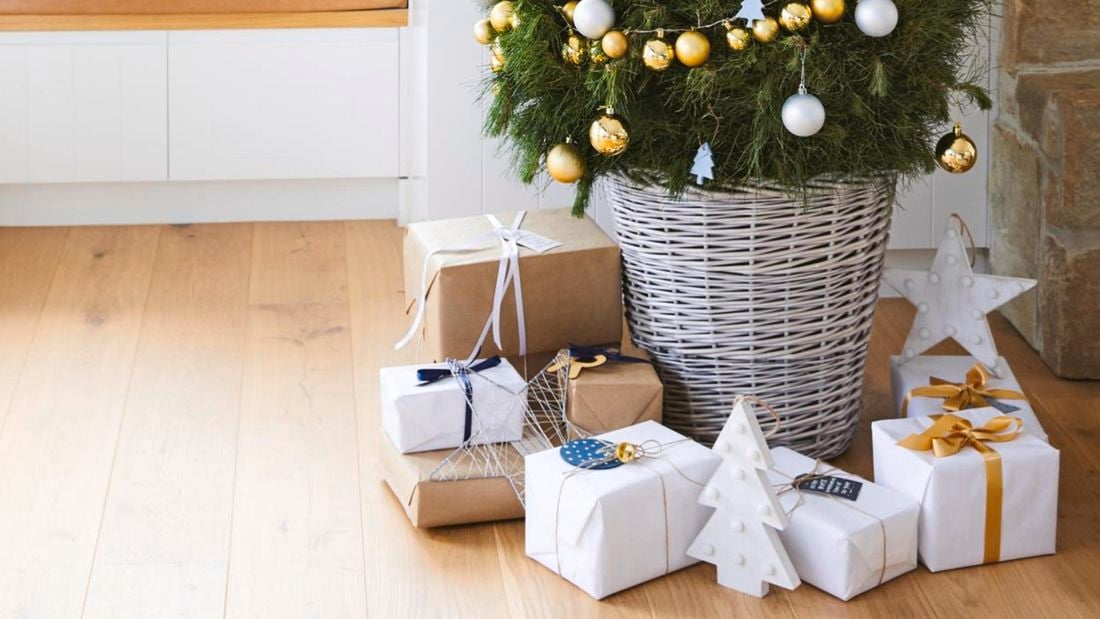 Christmas tree with presents underneath and a window seat next to it.