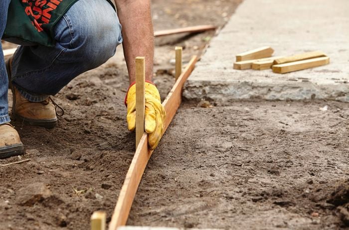 Bunnings team member positioning a peg into the curved edging of a path yet to be filled with concrete.