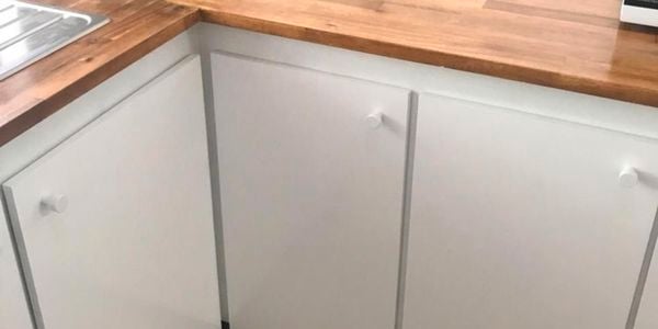 A kitchen with white cabinets and a timber benchtop