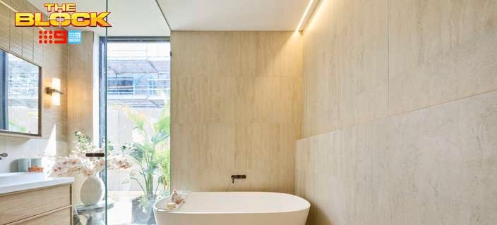 A modern bathroom with a bath, mirror on the wall, shower screen, drawers with a sink in it under a tap, in the room.