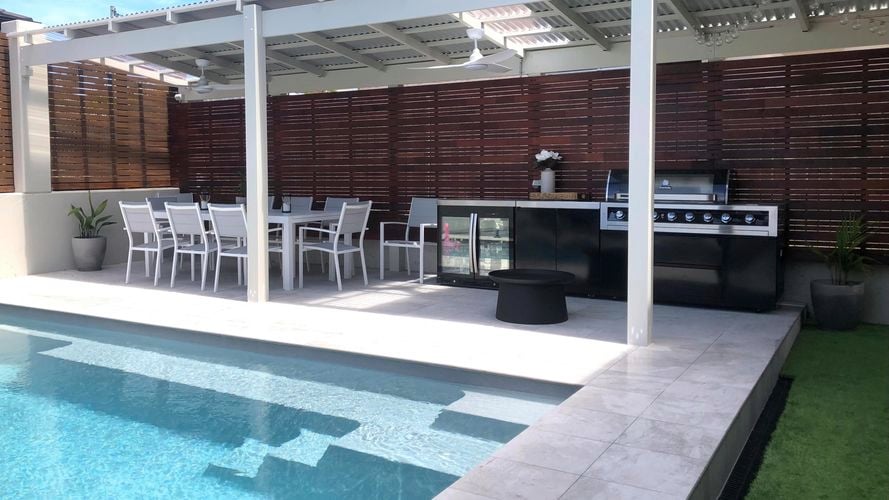 Outdoor area with bbq, pool, mini fridge and outdoor dining set.