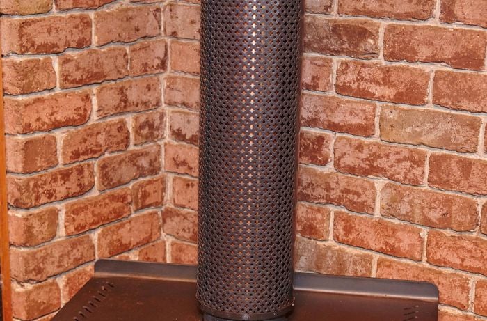 The flue of a wood heater surrounded by safety mesh
