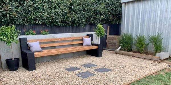 Besser block bench in pebbled backyard surrounded by lawn