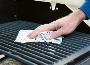 Close up of a cleaning cloth being used on a barbeque grill.