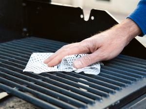 Close up of a cleaning cloth being used on a barbeque grill.