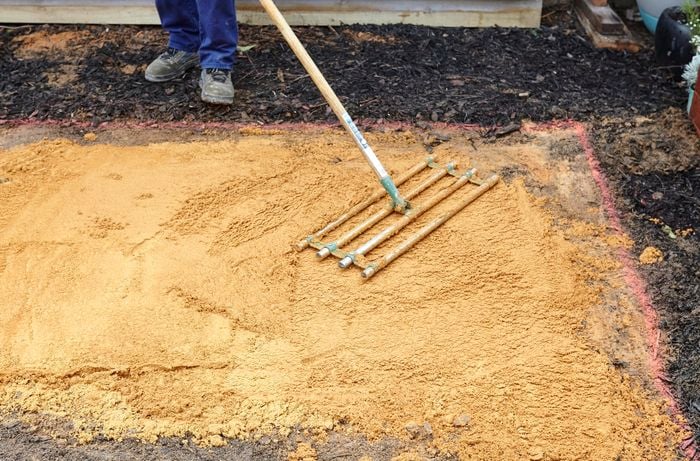 Person levelling sand with a screed