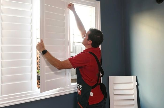 Person attaching shutter panels to the frame with hinge pins