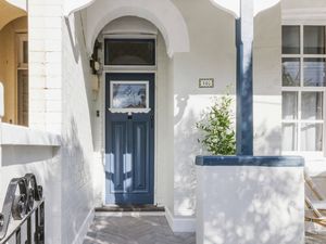 Freshly painted heritage home entryway with a blue front door and white brickwork.