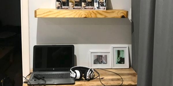 A floating timber shelf above a desk with collectibles in a home office