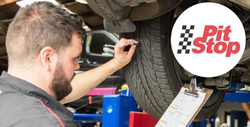 mechanic reviewing car tyres while car is on a hoist.