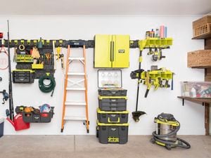 An organised garage wall showcases the Ryobi LINK rail system neatly holding tools, storage bins, shelves, a ladder, a hose, and other equipment