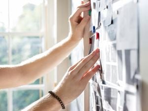 Person sticking post-it note on wall.