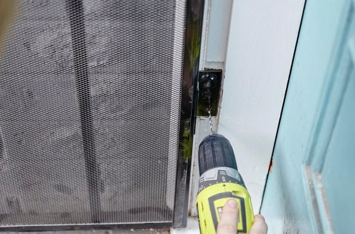 Holes being drilled into a door frame for screwing down the security door's hinges