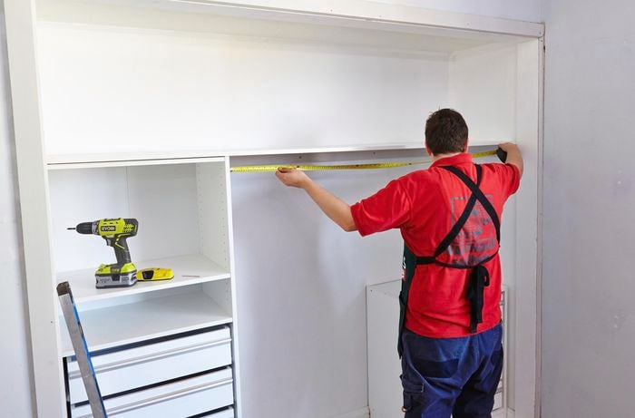 Person laying down top shelf of wardrobe unit.