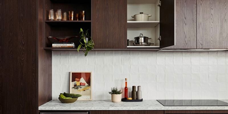 Brown modern kitchen with Marble benchtops with crockery on it and an oven in it.
