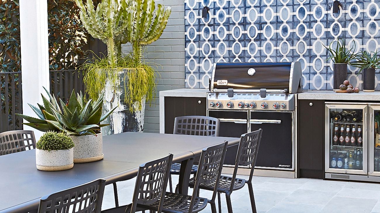Grey tiled outdoor kitchen with a barbecue and under bench fridge