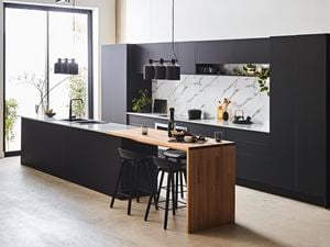 Kitchen with black cabinets, marble splashback and timber.
