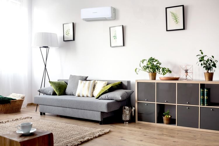 Lounge room with grey couch, timber cube storage unit and tall lamp with white lampshade