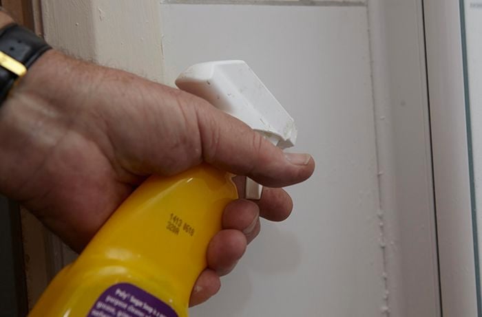 Person spraying some liquid onto a wall.