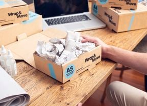 A person packs skincare products in a small Wrap & Move box filled with Wrap & Move’s kraft paper