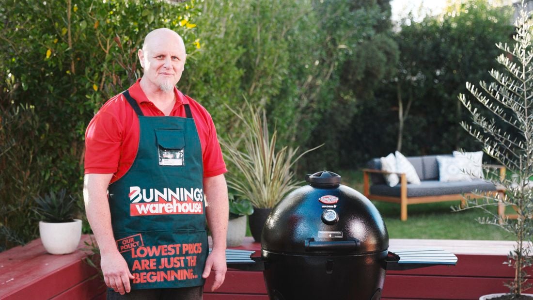 Man standing next to a kamado smoker