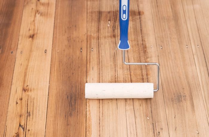  A person is applying extra coats of sealer to build a durable and long-lasting floor finish.