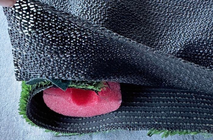 Black shelf mat being attached to a foam turf mat with a red pool noodle visible