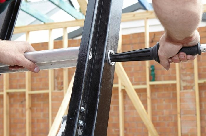 A person inserting a ladder limb into a hole in the side of a ladder