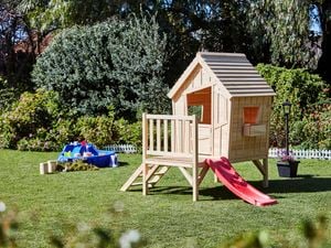 Wooden cubby house in a backyard with a sand pit next to it.