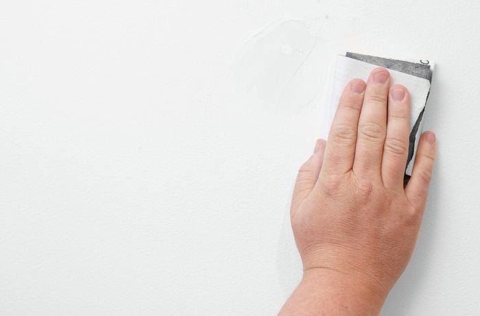 Sanding the patched hole in the wall