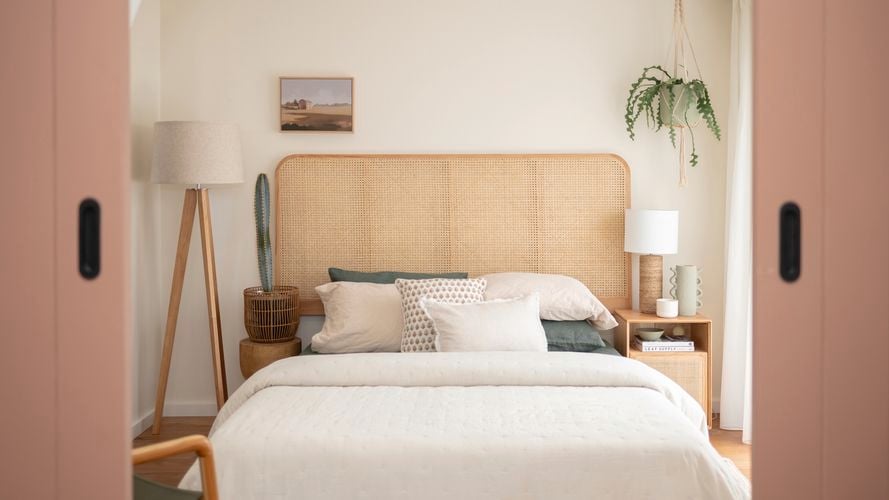 In a neatly decorated room, there are five basketballs hanging on the wall. A guitar is placed in the corner, alongside a study desk and chair. Additionally, there is a small bed with a brown beanbag