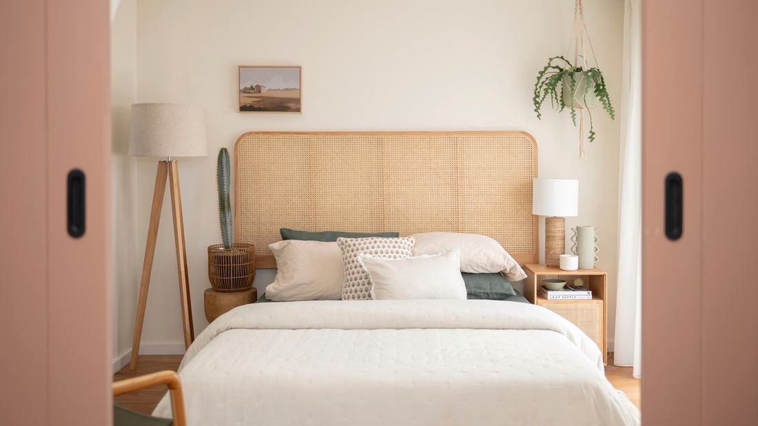 In a neatly decorated room, there are five basketballs hanging on the wall. A guitar is placed in the corner, alongside a study desk and chair. Additionally, there is a small bed with a brown beanbag
