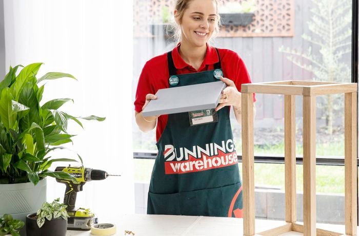 A Bunnings team member adding a solid base to a wooden plant stand
