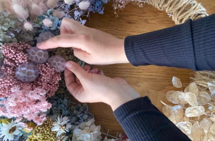 A wreath with dried flowers being added to it
