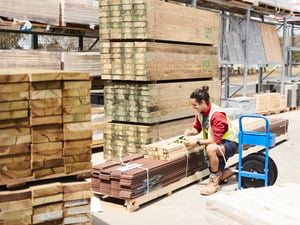 A team member securing lengths of timber to a pallet with plastic ties, in a Bunnings timber yard