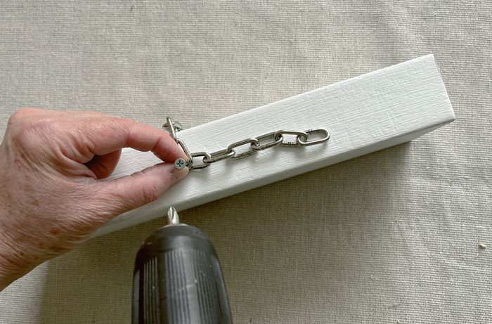 A hand in a black glove applying adhesive to a black door stop for a red and black vampire block.