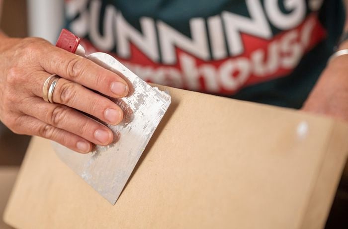 A Bunnings Team Member holding a spatula over a piece of wood