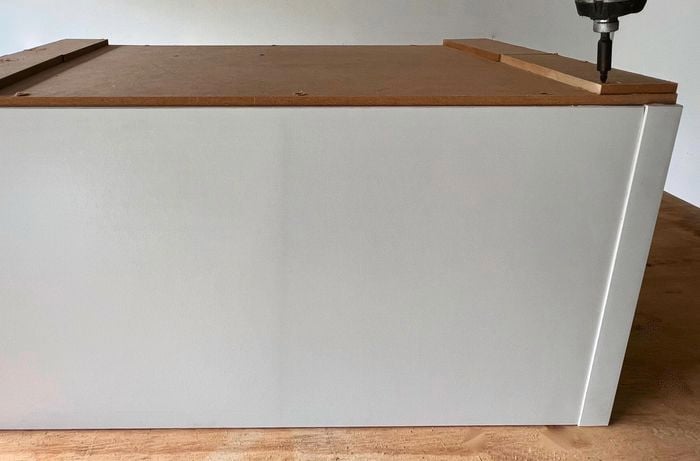 A person uses woodworking adhesive to secure a base and rails on a Flexi Storage clever cube unit