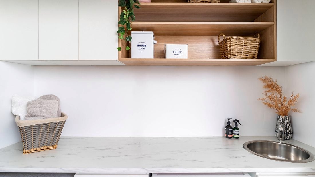 A laundry with a marble white benchtop with a basin in it, a dryer and washing machine in it.