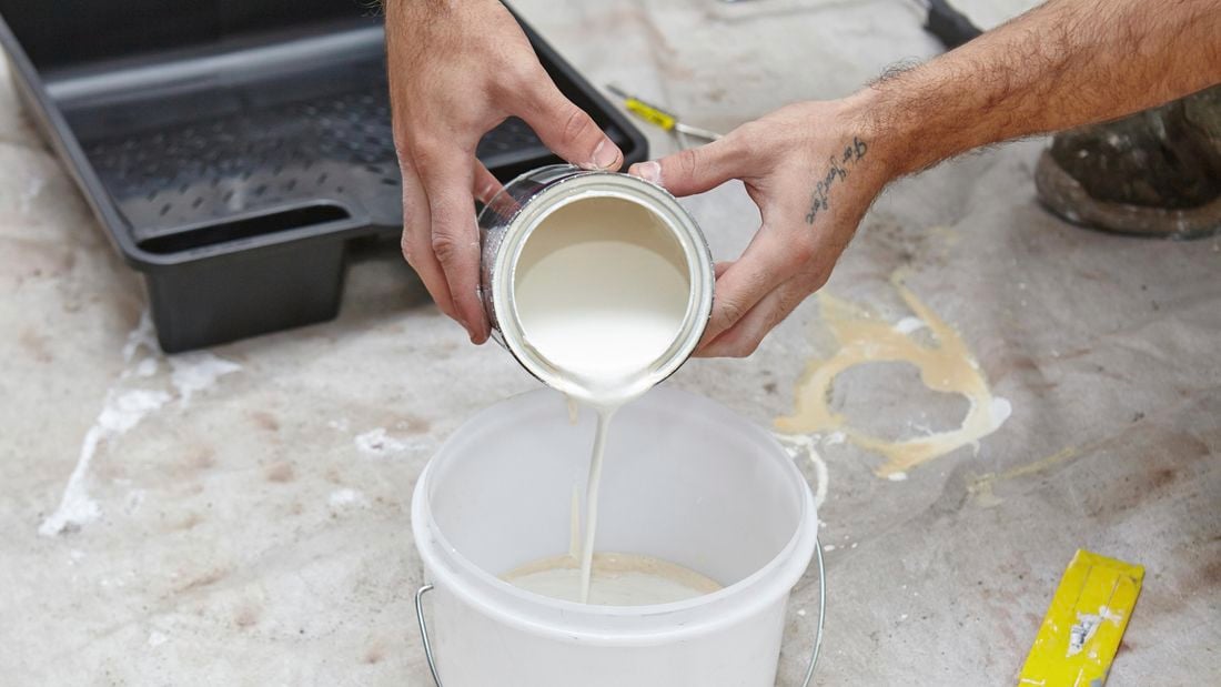 White paint being poured into a bucket