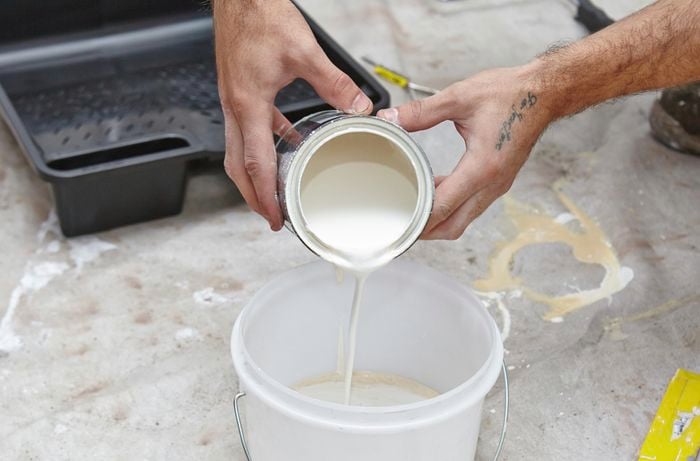 White paint being poured into a bucket