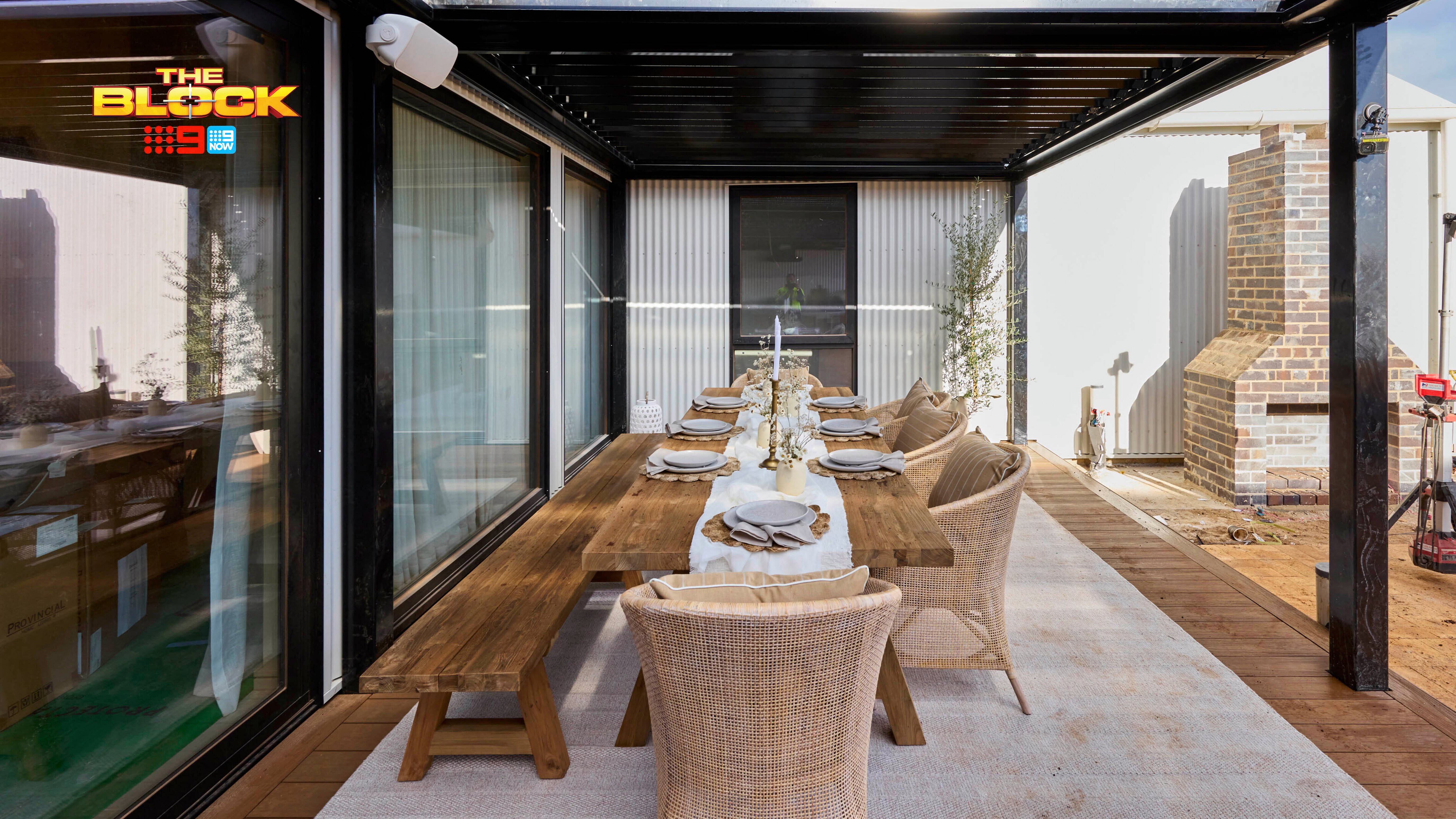 An outdoor area with a table and chairs around it under cover.