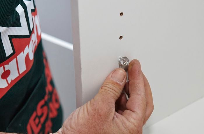 Person putting shelf supports in place.