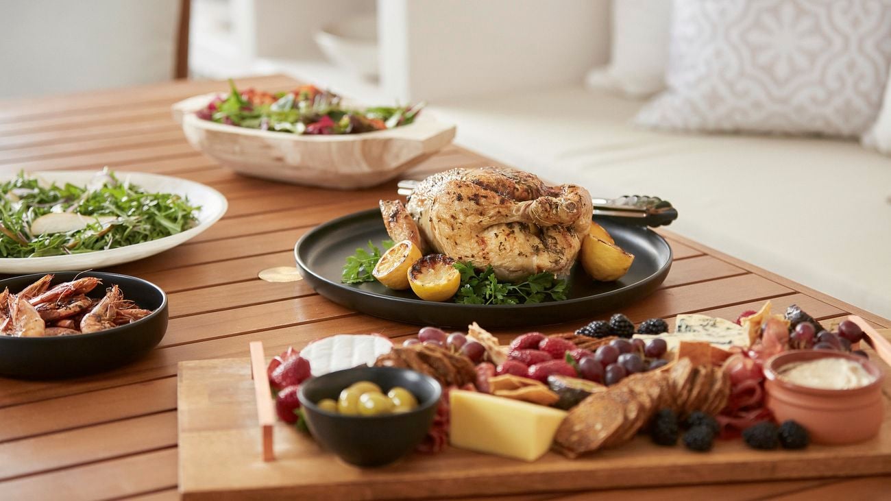 Barbecued chicken and prawns, salads and an antipasto platter on an outdoor dining table