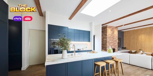 Kitchen with navy island, marble top, wooden stools, and open-plan living.