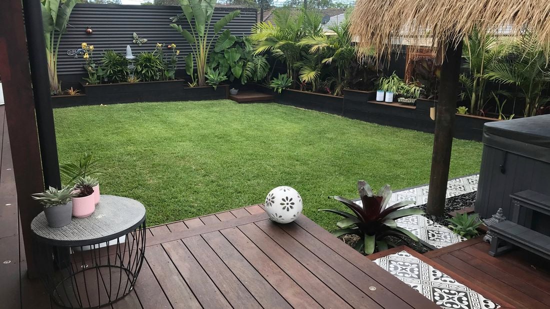 Backyard in shot with lush green grass and outdoor entertaining area