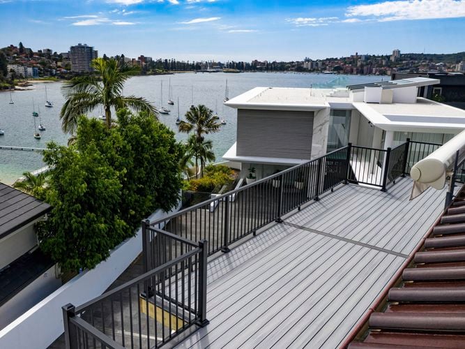Decking path leading to a house near the water with boats in it.
